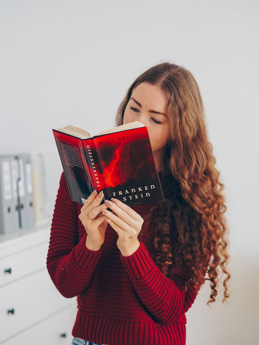 donna in maglione rosso che tiene il libro rosso