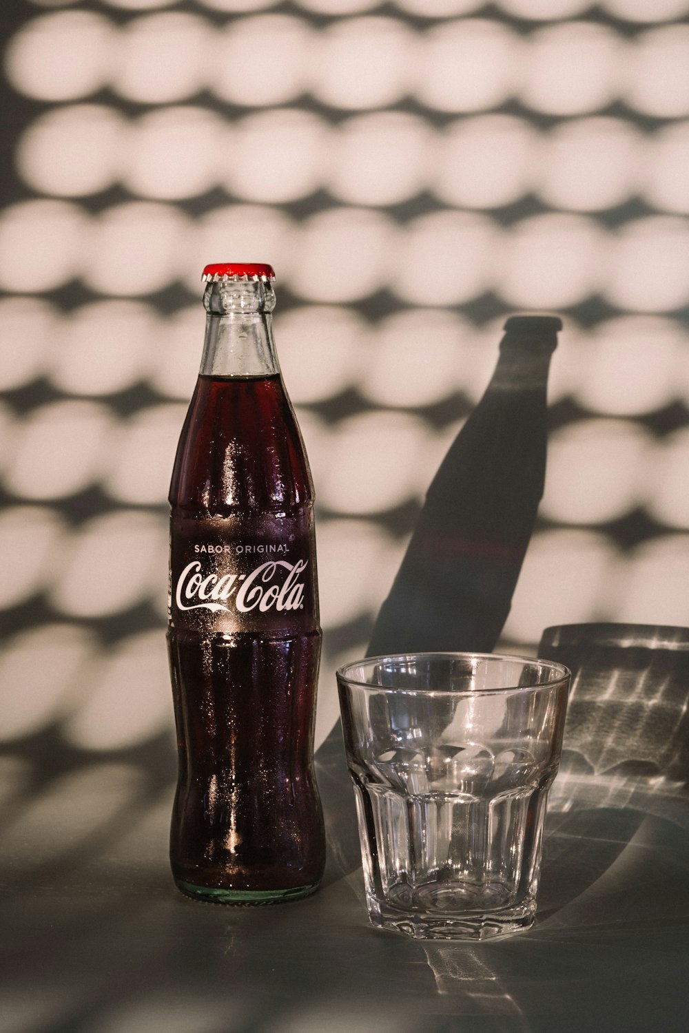 coca cola bottle beside drinking glass