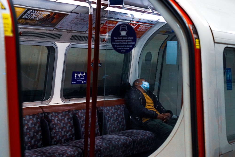 uomo in giacca nera che si siede sul sedile del treno