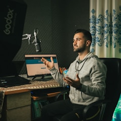 man in gray sweater sitting on chair in front of laptop computer