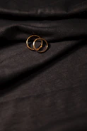 Elegant unisex gold and black rings displayed on a soft nude fabric background