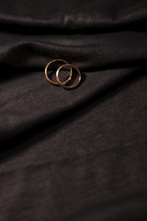 Close-up of wedding rings resting on a textured gold fabric, reflecting soft ambient light.