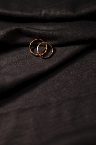 Close-up of delicate gold rings stacked elegantly on a soft fabric background.