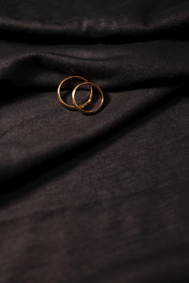 Close-up of elegant gold and silver rings stacked delicately on a soft marfil fabric background.