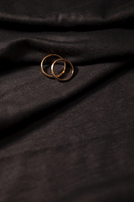 Close-up of elegant gold and silver rings arranged on a velvet cushion, glowing softly under warm light.
