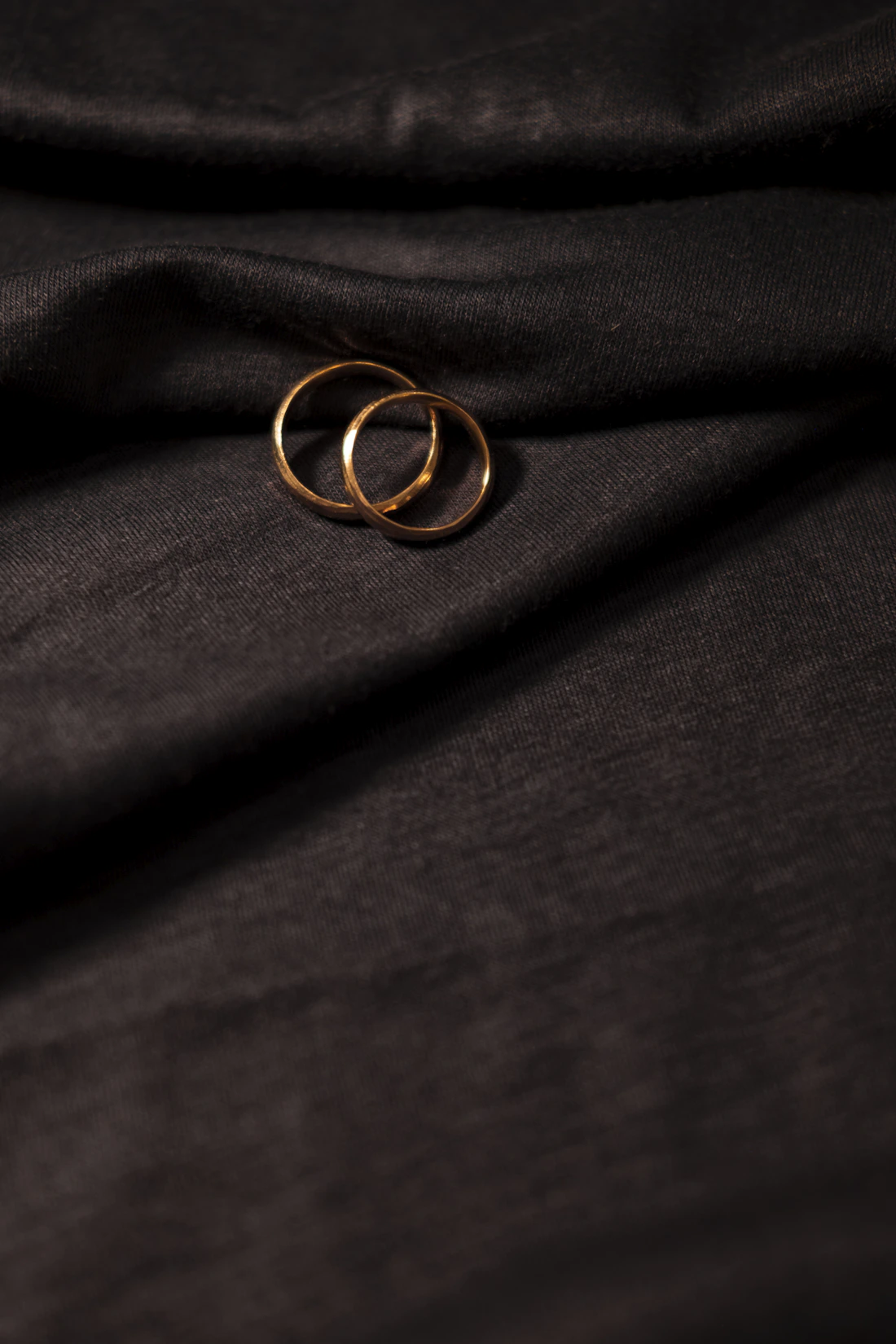 Real photograph of gold rings on dark fabric