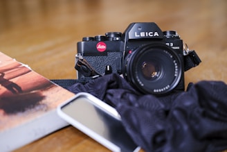 A vintage Leica camera resting on a travel journal beside a cup of coffee.