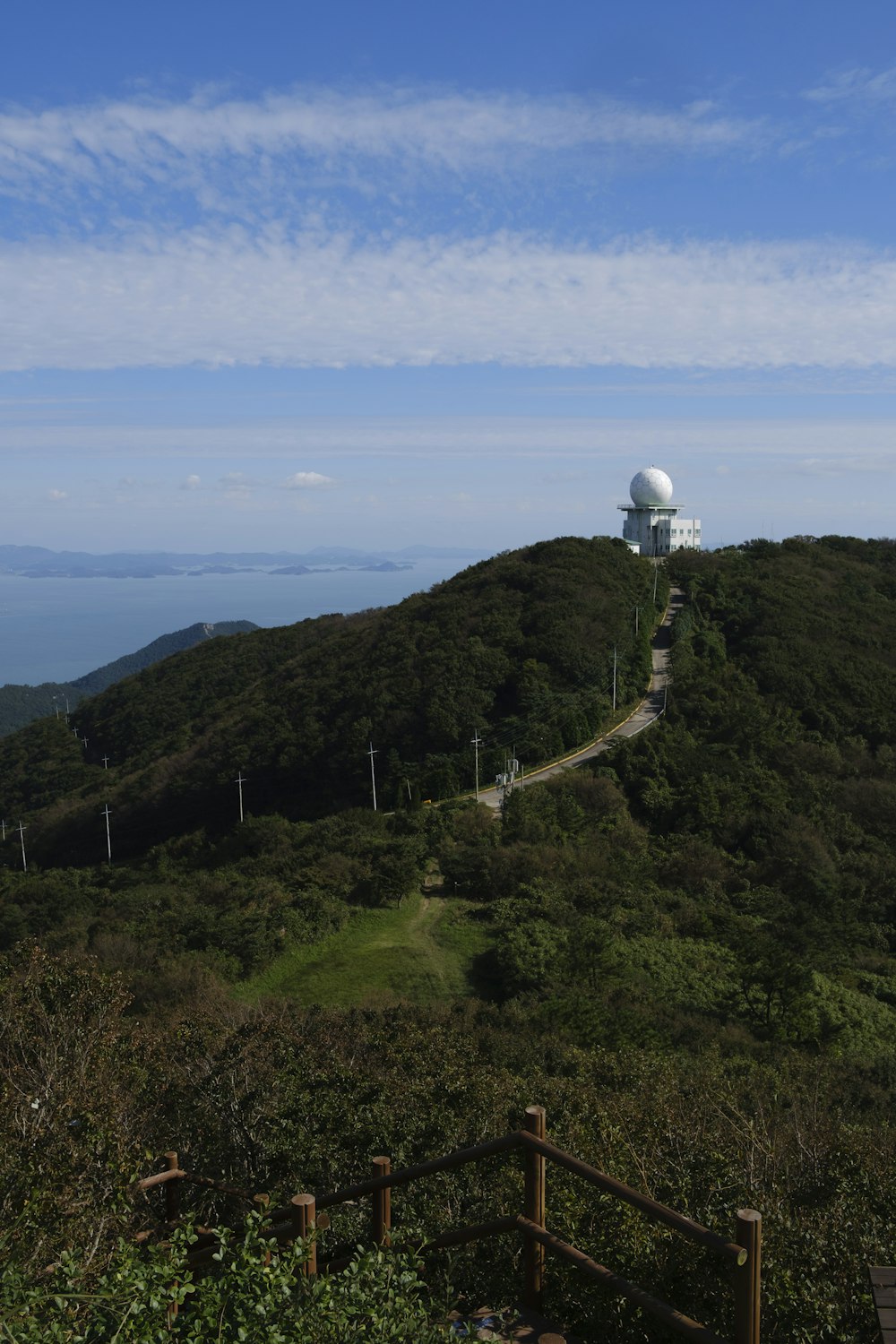 white and black lighthouse on green mountain under blue sky during daytime