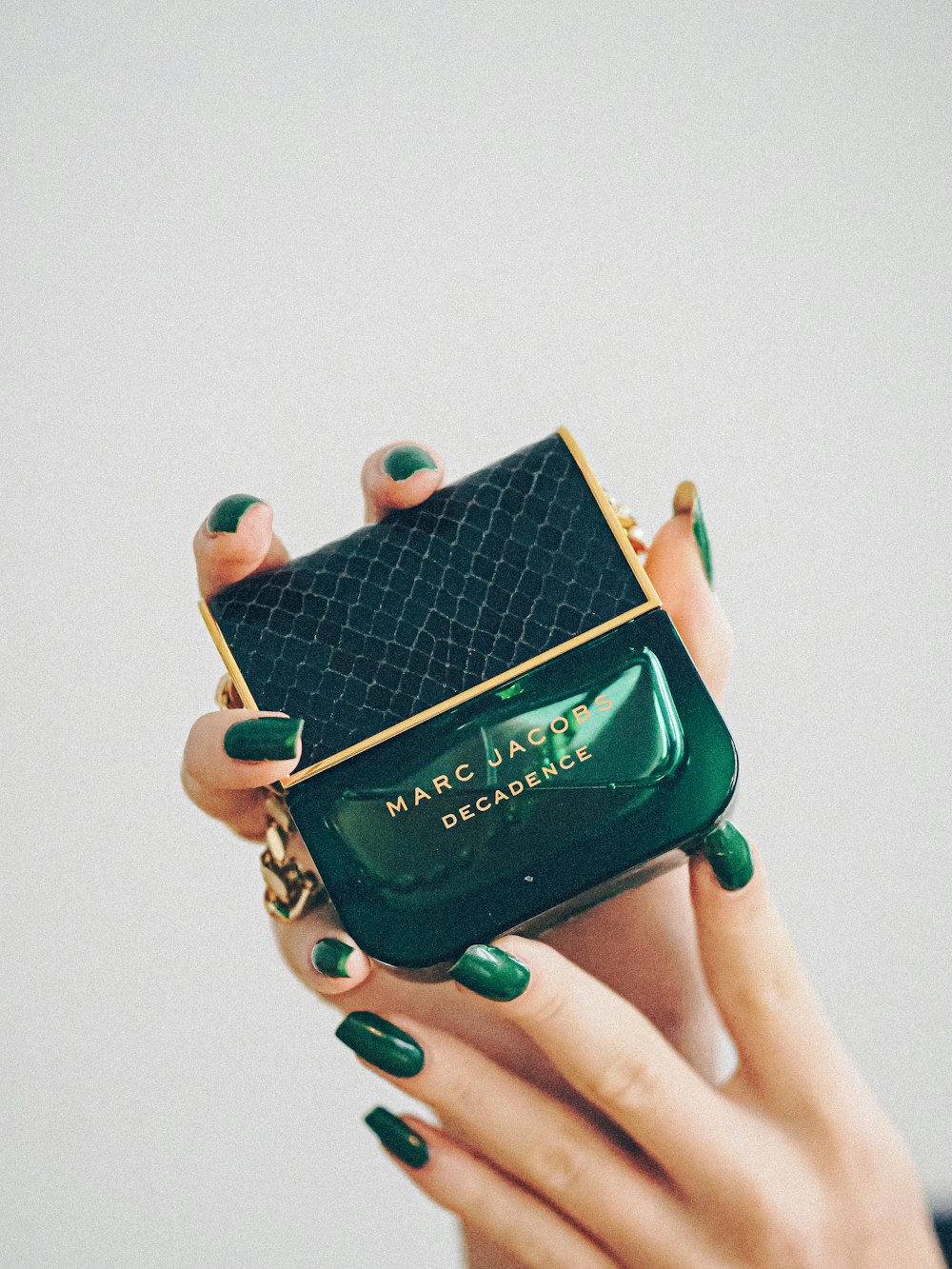 a woman holding a green purse with a green manicure