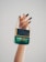 A hand with dark green painted nails holds a luxurious Marc Jacobs Decadence perfume bottle, which features a distinctive handbag design with gold chain detailing.
