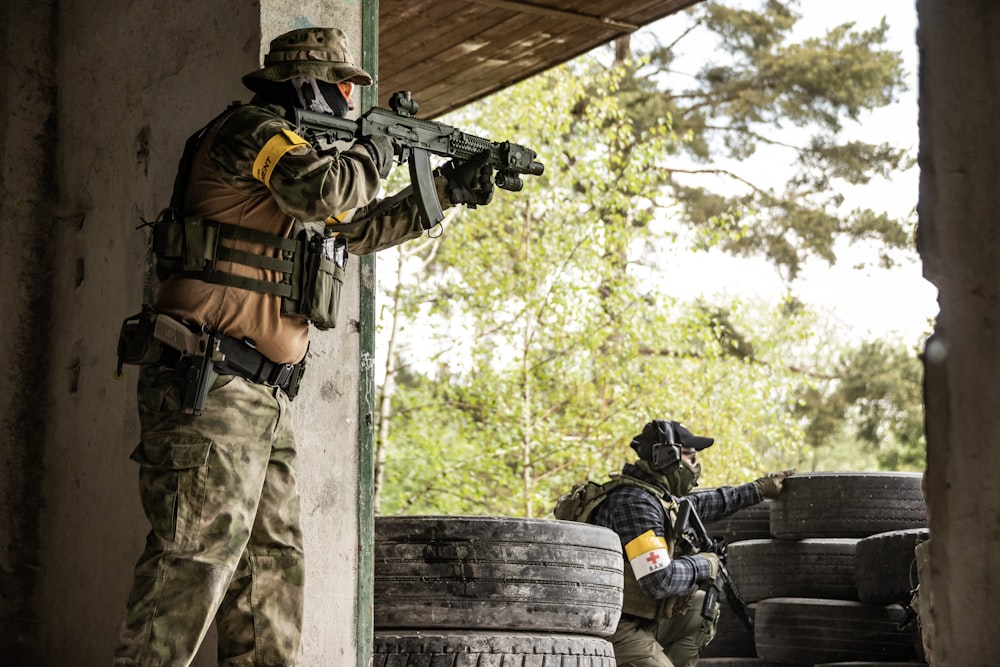 two men in body armor with weapons take cover and concealment