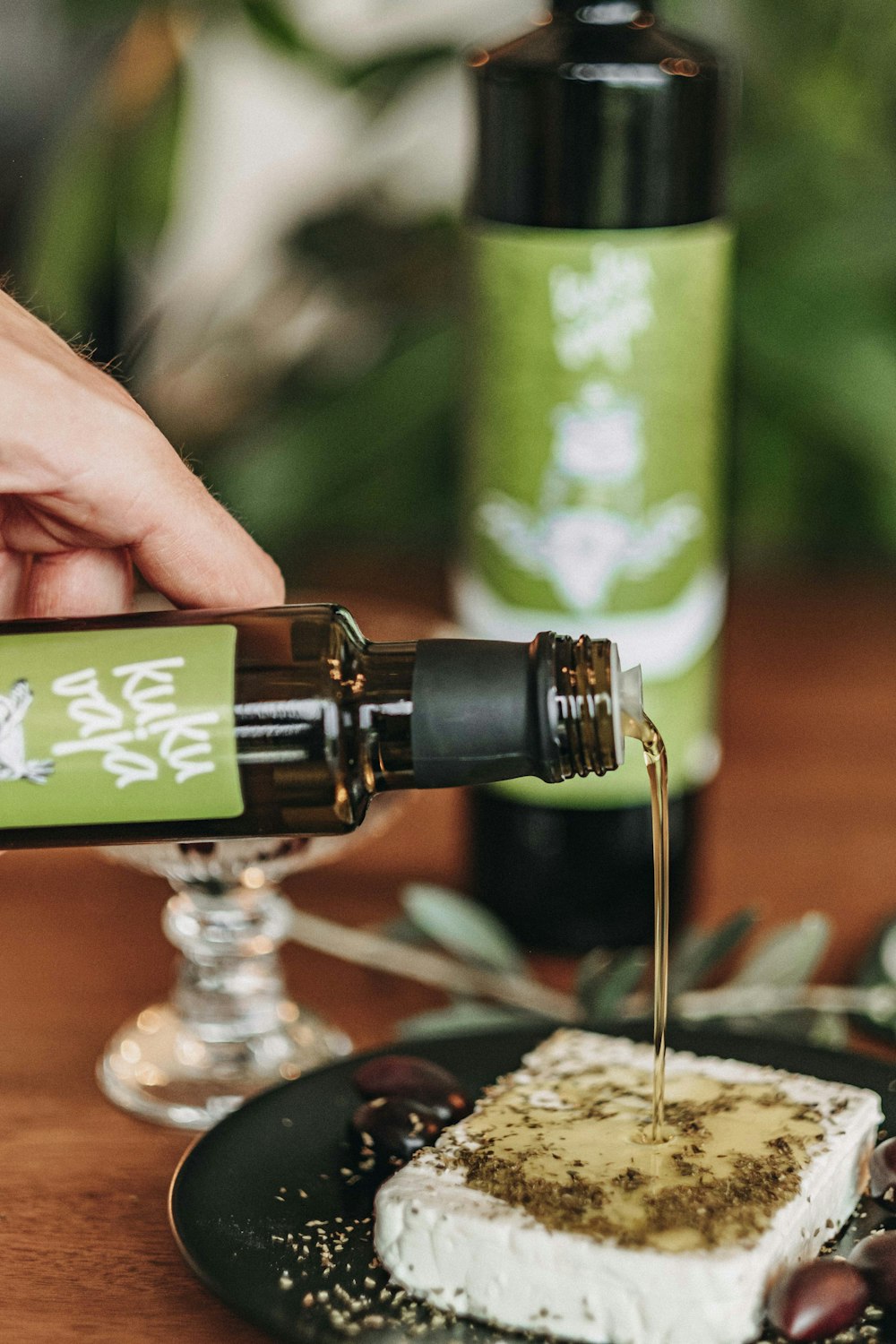 person pouring water on green and black bottle