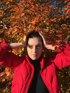 A vibrant red jacket catching the light on a city sidewalk in autumn.