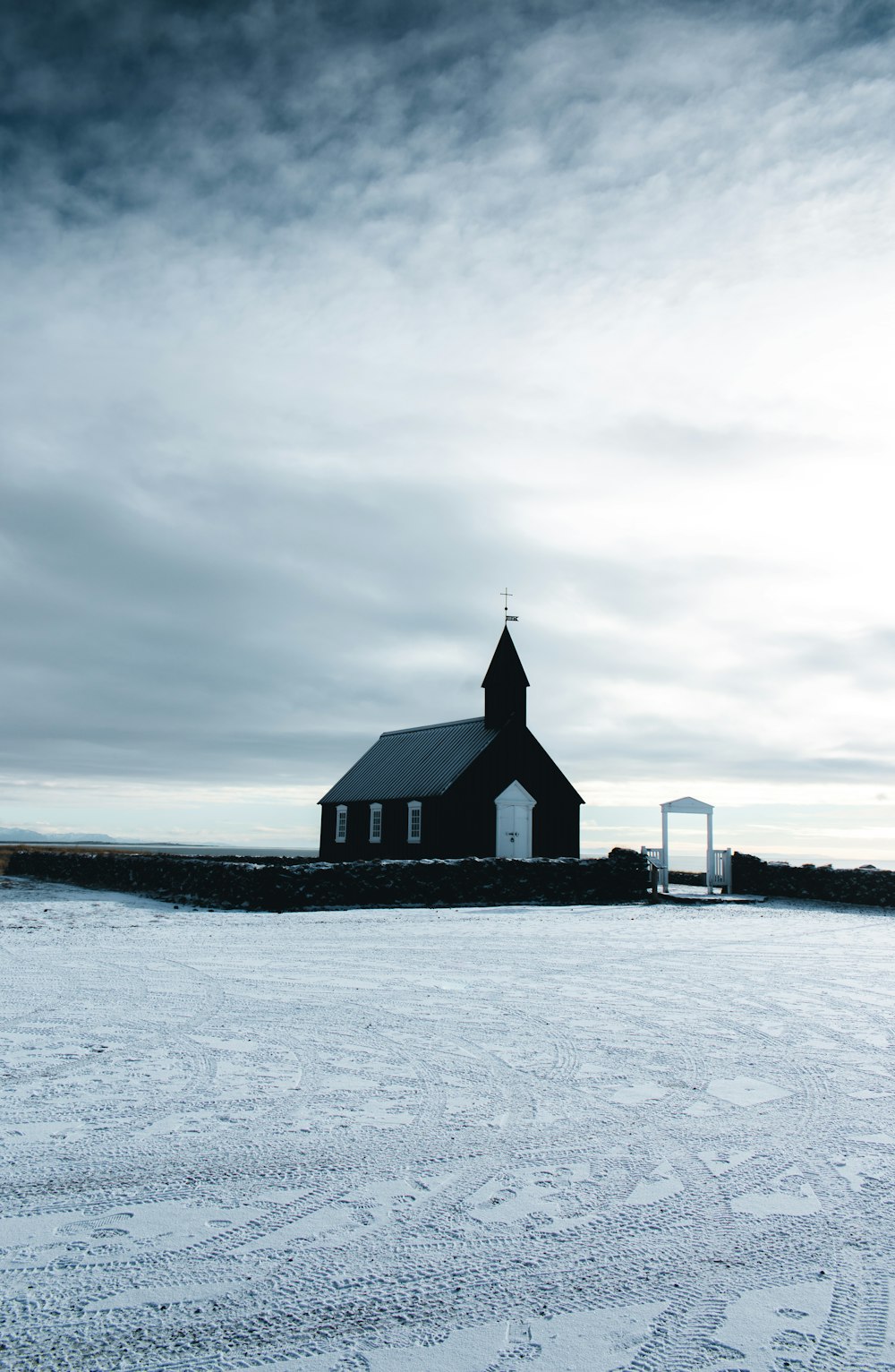 black and white wooden house on snow covered ground under cloudy sky