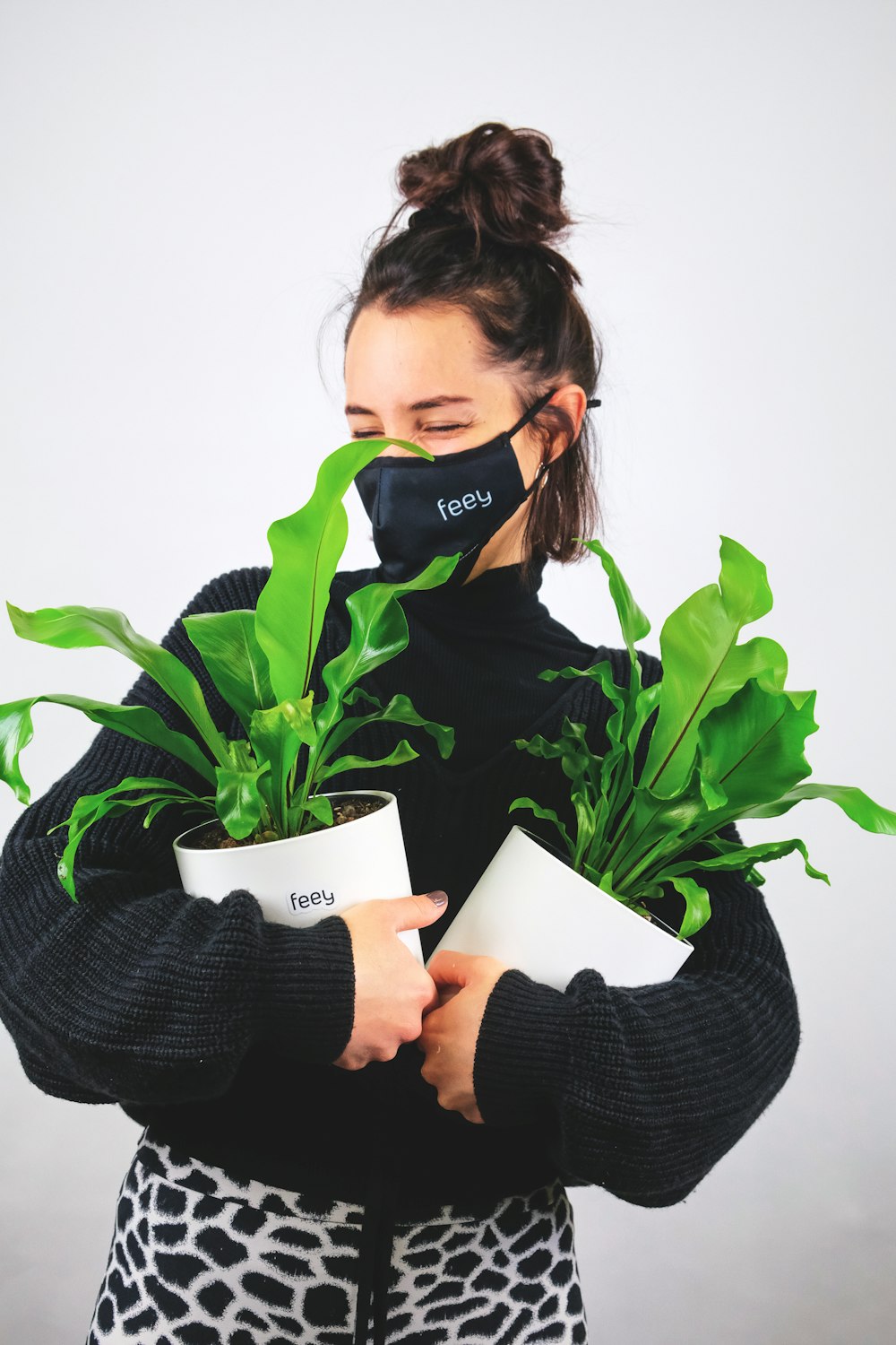 woman in black sweater holding white ceramic mug with green plant