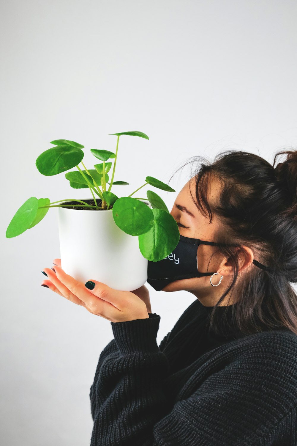 woman in black sweater holding green plant