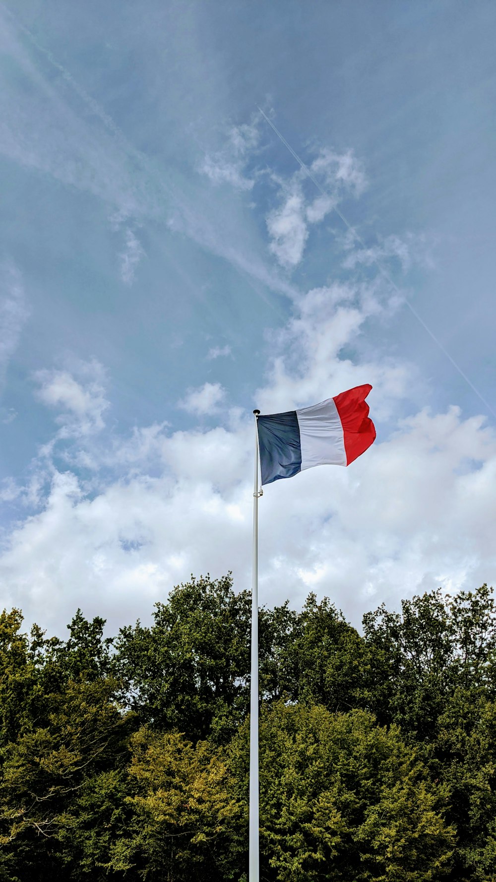 red and white flag on pole under white clouds and blue sky during daytime