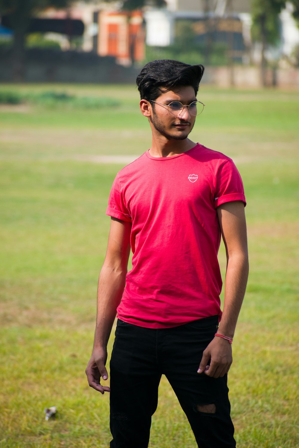 man in red crew neck t-shirt and black pants standing on green grass field during