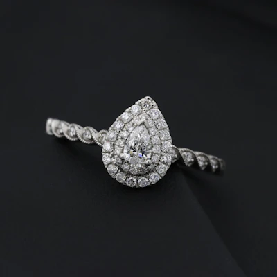 Pear-shaped diamond reflecting warm golden hues on a dark background.