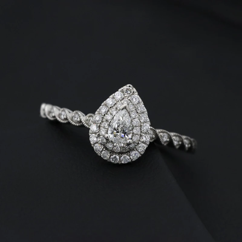 Pear shaped halo diamond engagement ring on a dark background
