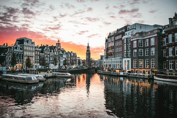 White boat on river between buildings during daytime — Amsterdam, Netherlands