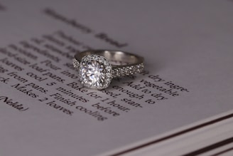 silver diamond ring on white book page