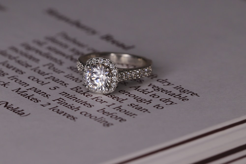 silver diamond ring on white book page
