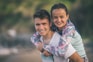 man in white shirt hugging woman in blue and red long sleeve shirt