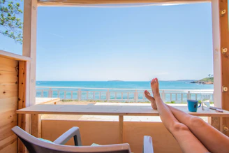 Couple relaxing in a cozy cabin with a balcony overlooking the endless blue sea.