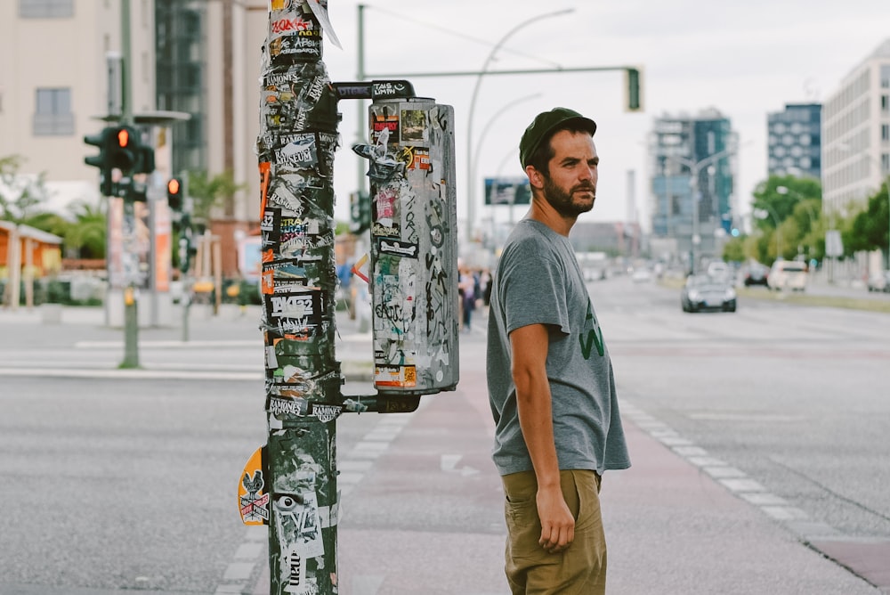 man in blue crew neck t-shirt and brown shorts standing on street during daytime