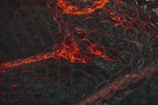 A close-up view of bubble wrap featuring pockets illuminated with red light. The transparent plastic creates a textured and patterned effect with highlights and shadows.