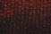 A close-up view of a sheet of bubble wrap with a dark, dramatic lighting. Each bubble is illuminated with an intense red and black contrast, highlighting the texture and translucency of the material.