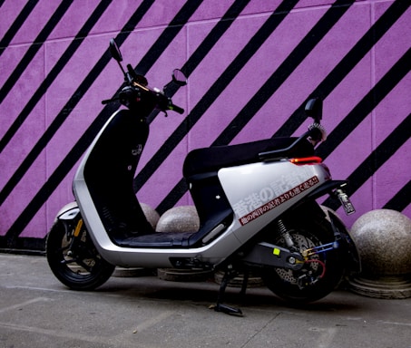 A modern electric scooter parked beside a green neon-lit wall reflecting the brand's color theme.