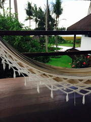 A peaceful garden shaded by argan trees with hammocks and a cozy outdoor coworking setup overlooking the hills.