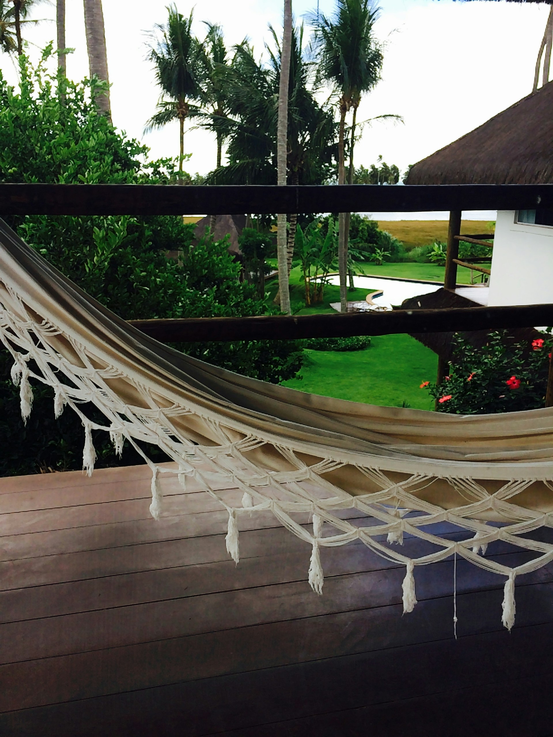 Peaceful garden area with a hammock and blooming flowers, perfect for relaxing near the sea.