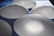 Several translucent, oval-shaped silicone implants are arranged on a textured blue surface, casting soft shadows.