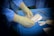 Hands wearing surgical gloves preparing medical instruments on a blue draped table. Various sterilized tools and supplies, such as gauze and packaging, are neatly arranged nearby.