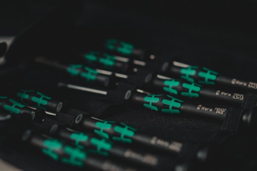 A set of black and green handled screwdrivers organized in a tool case. The handles have a distinctive design with green sections, and the name 'Wera' is visible along with the sizes on the shafts.