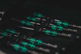 A set of black and green handled screwdrivers organized in a tool case. The handles have a distinctive design with green sections, and the name 'Wera' is visible along with the sizes on the shafts.