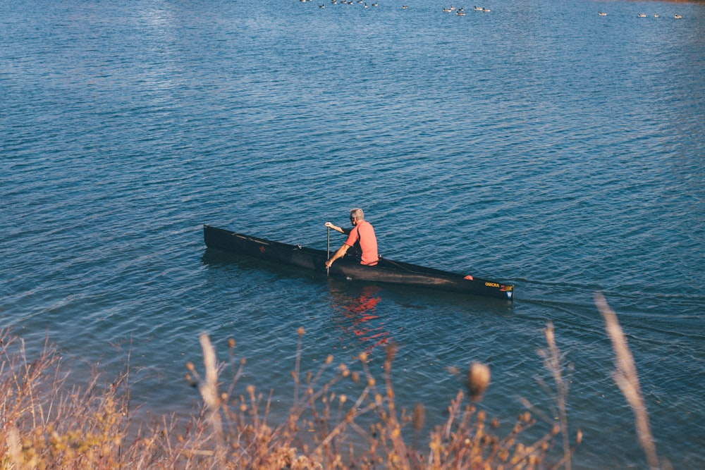 woman in black and red dress sitting on black boat on sea during daytime