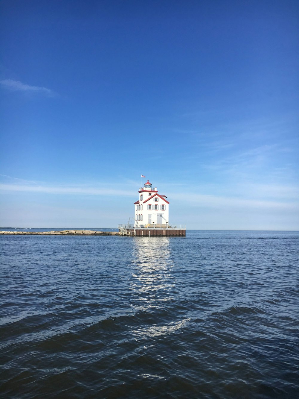 white and red concrete building on sea under blue sky during daytime