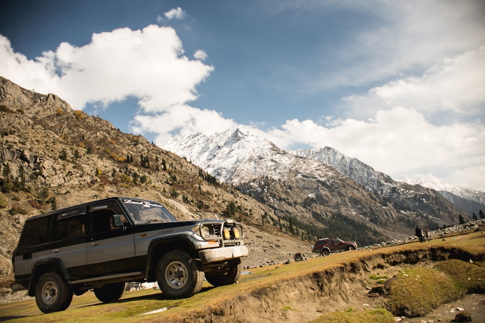 white suv on brown field near snow covered mountain during daytime