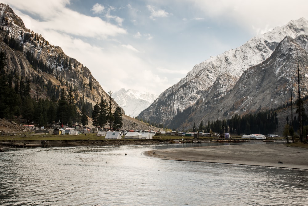 body of water near mountain under cloudy sky during daytime