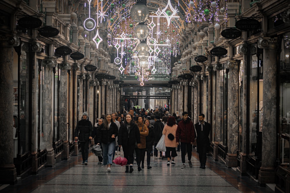 people standing on hallway with lighted ceiling lamps