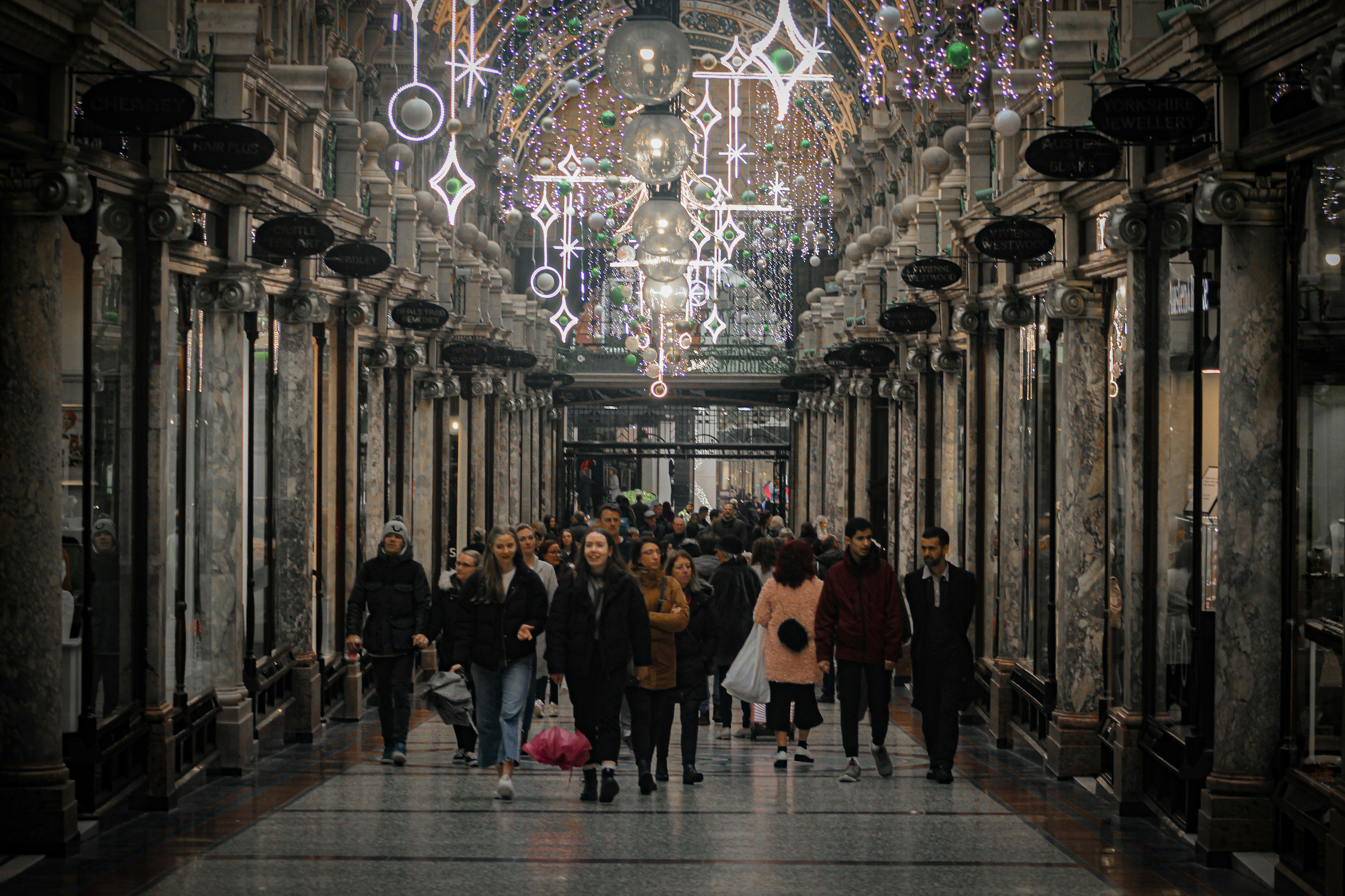 people standing on hallway with lighted ceiling lamps