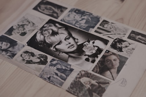 A collection of vintage black and white photographs displayed on a wooden surface. The central image features a woman with styled hair holding a rose. Surrounding photos showcase portraits of various women in classic poses, conveying a retro aesthetic.