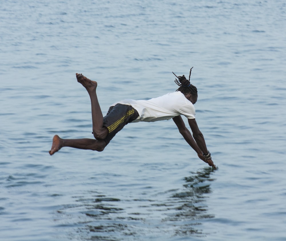 man in white t-shirt and yellow shorts jumping on water