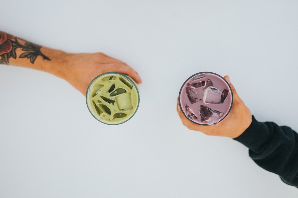 four person holding green and brown liquid in cups