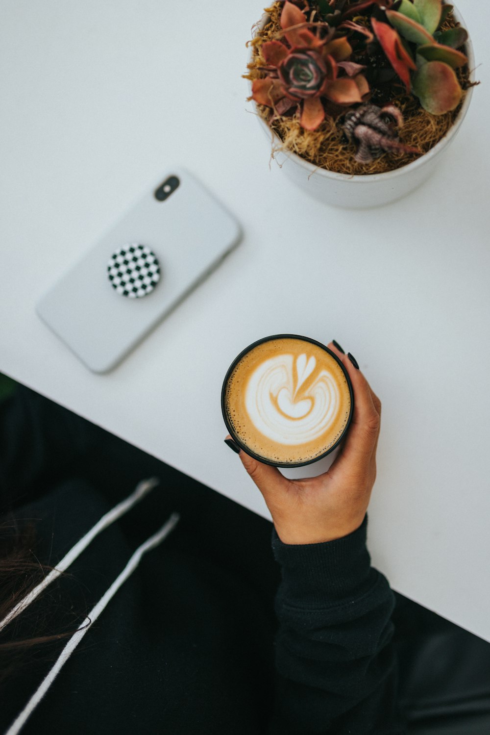 personne tenant une tasse en céramique blanche avec du café