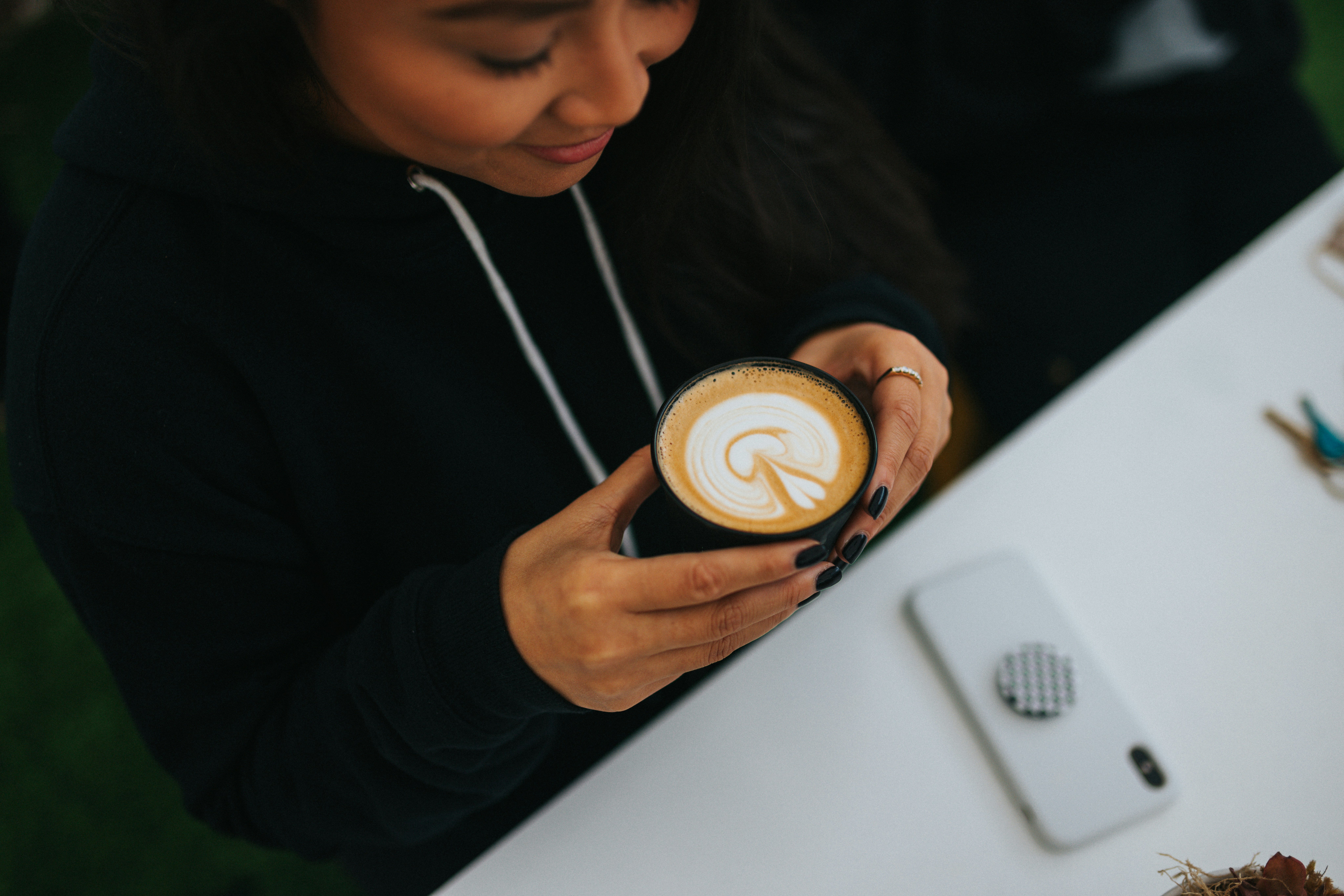 woman in black long sleeve shirt holding white ceramic cup with cappuccino